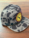 Camouflage cap with a logo on a wooden surface