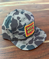 Camouflage cap with a red and yellow logo on a wooden surface
